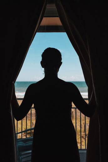 silhouette of person standing in front of a window with curtains pushed to the side. modern windows and doors. niagara region